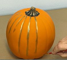 a person painting a pumpkin with gold paint