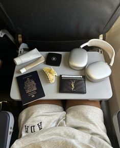 a person laying in bed with headphones, passport and other items on the table