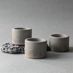 three cups sitting on top of each other next to a rock in the middle of a room