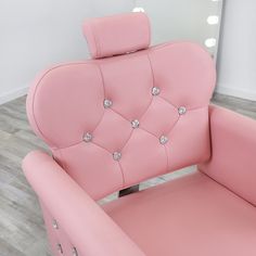 a pink chair with diamond buttons on the armrests and back rests in front of a mirror