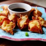 some fried food on a blue and pink plate with dipping sauce in the bowl next to it