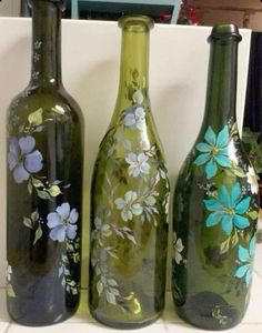 three glass bottles with flowers painted on them