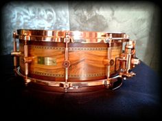 a close up of a wooden drum on a black surface with gold trimmings