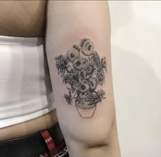 a woman's arm with flowers in a vase tattoo on the left upper arm