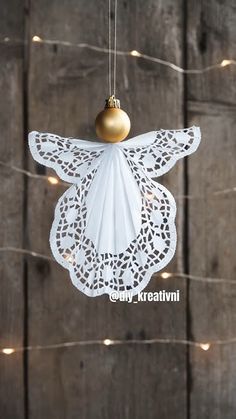 a white angel ornament hanging from a string on a wooden wall with lights