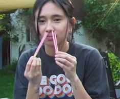 a young woman holding a pink straw in her mouth