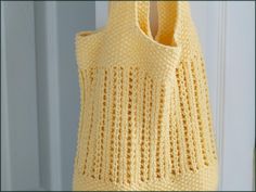 a crocheted yellow bag hanging from a hook on a door handle with the handles down