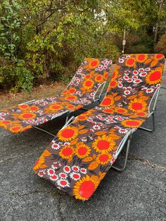 two lawn chairs with sunflowers on them sitting in the middle of a parking lot