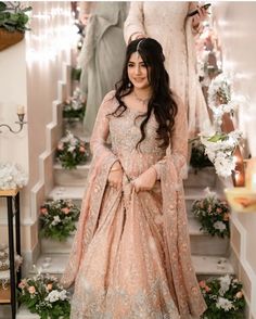 a woman standing in front of stairs wearing a pink gown and matching headpieces