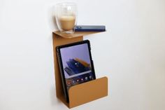 a cell phone is sitting on top of a cardboard shelf with a cup of coffee next to it