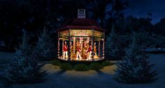 a lit up gazebo in the middle of some trees