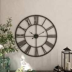 a large clock mounted to the side of a wall next to a potted plant