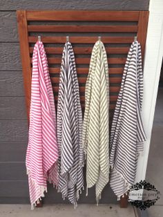 three striped towels hanging on a wooden rack