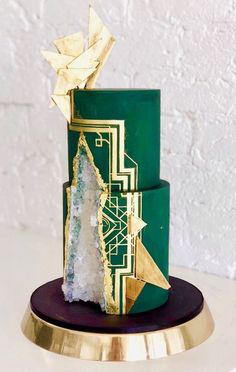 a green and gold cake on a table with white wall in the backround