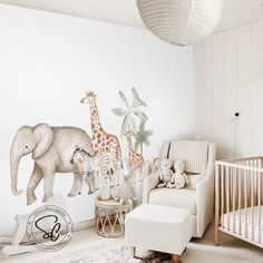 a baby's room with an elephant, giraffe and zebra mural on the wall