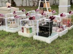 several clear boxes filled with different types of purses and bags sitting on the grass