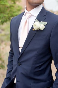 a man in a blue suit with a white rose boutonniere on his lapel