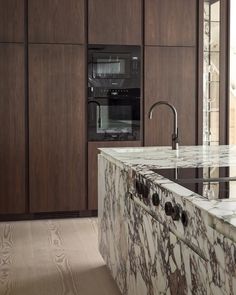 a kitchen with marble counter tops and an oven in the back wall, along with wooden cabinets