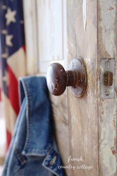 an old wooden door with a rusted metal knob and jeans hanging on the side