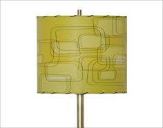 a lamp that is sitting on top of a metal pole with a yellow shade over it