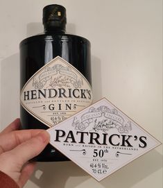 a hand holding up a bottle of gin with a label on it that says patrick's 50 year old