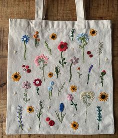 a white bag with embroidered flowers on it