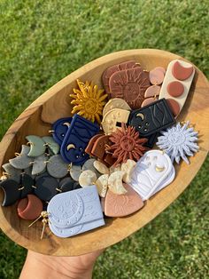 a person holding a wooden bowl filled with different types of buttons and other decorative items