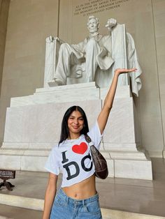 a woman posing in front of the lincoln memorial with her hand up to the sky