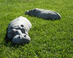 two ceramic hippopotamus laying in the grass