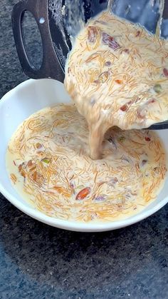 a person pouring sauce into a bowl on top of a counter