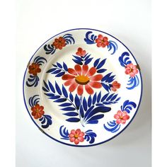 a blue and white plate with red flowers on the rim, against a white background