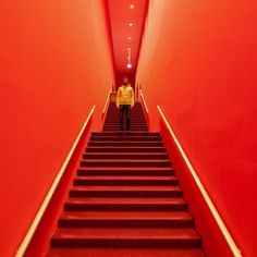 a man is standing on the stairs in an orange room with red walls and carpet