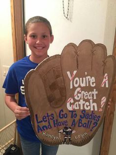 a young boy holding up a sign that says, you're a great catch lets go to softball and have a ball's