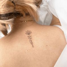 the back of a woman's neck with a small tattoo on her left shoulder