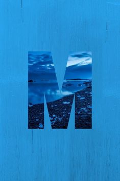 the letter m is made up of blue images on a wooden surface with water and clouds