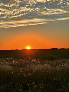 the sun is setting over an open field