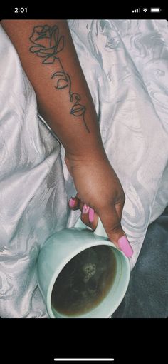 a woman with pink nails is holding a coffee mug in her left hand and writing on the right arm