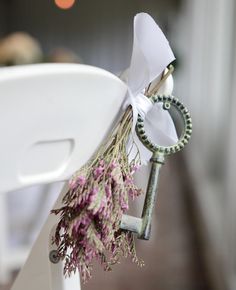 an old key is tied to the back of a white chair with flowers on it