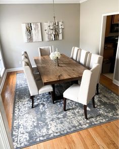 a dining room table with white chairs and a chandelier