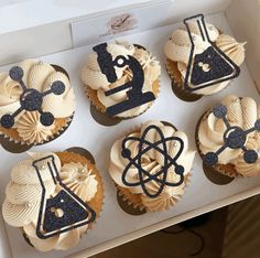 the cupcakes are decorated with black and white frosting, which include science symbols