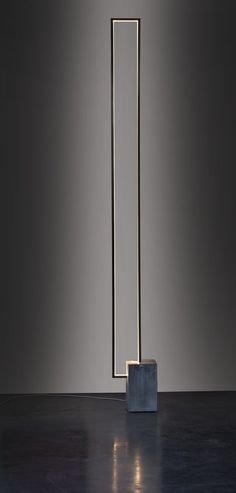 a tall metal object sitting on top of a floor next to a light fixture in the middle