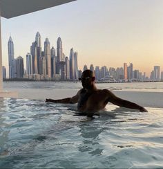 a man sitting in the middle of a swimming pool with a city skyline behind him