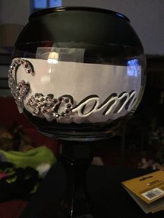 a wine glass sitting on top of a table with the word mom painted on it