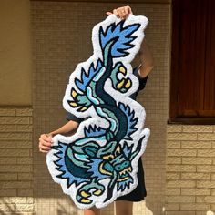 a woman holding up a large dragon shaped piece of art