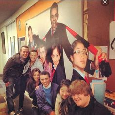 a group of people posing for a photo in front of a poster