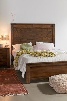 a bed with white sheets and pillows on top of it next to a brown rug