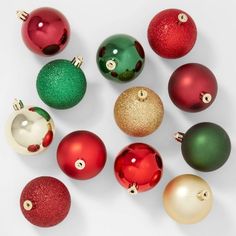 many different colored ornaments are arranged in a circle on a white surface, including one red and one green ornament