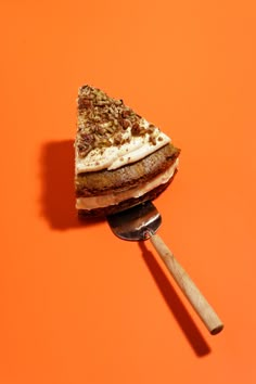 a piece of cake sitting on top of a spatula next to an orange wall