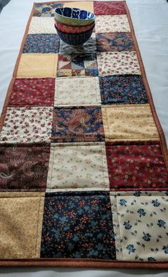 a bowl is sitting on top of a quilted table runner