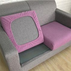 a gray couch with a pink cushion on it